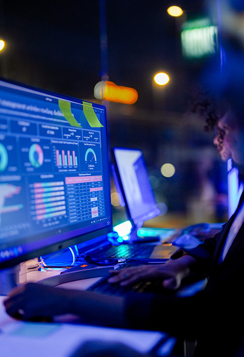 Person working on computer with data dashboards at night
