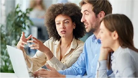 Three colleagues looking at a laptop screen and discussing something